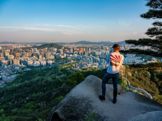 a man standing on top of a cliff overlooking a city